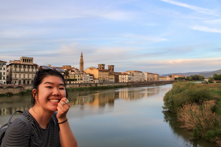 Student smiles in front of the Arno River in Florence, Italy