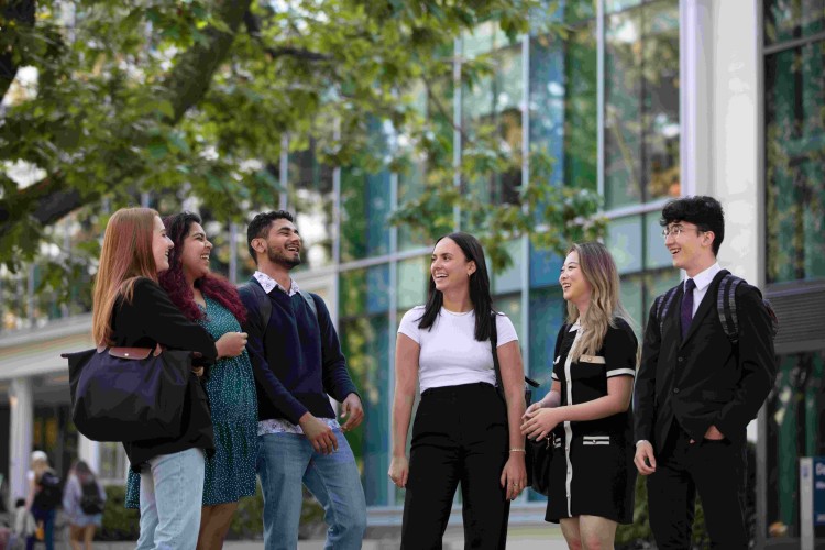 Group of BCom students laughing outside the Henry Angus Building